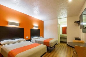 A hotel room with two beds, a desk, and a bathroom visible through an open door. - 2 Full Beds | Smoking, Micfridge (Madisonville)