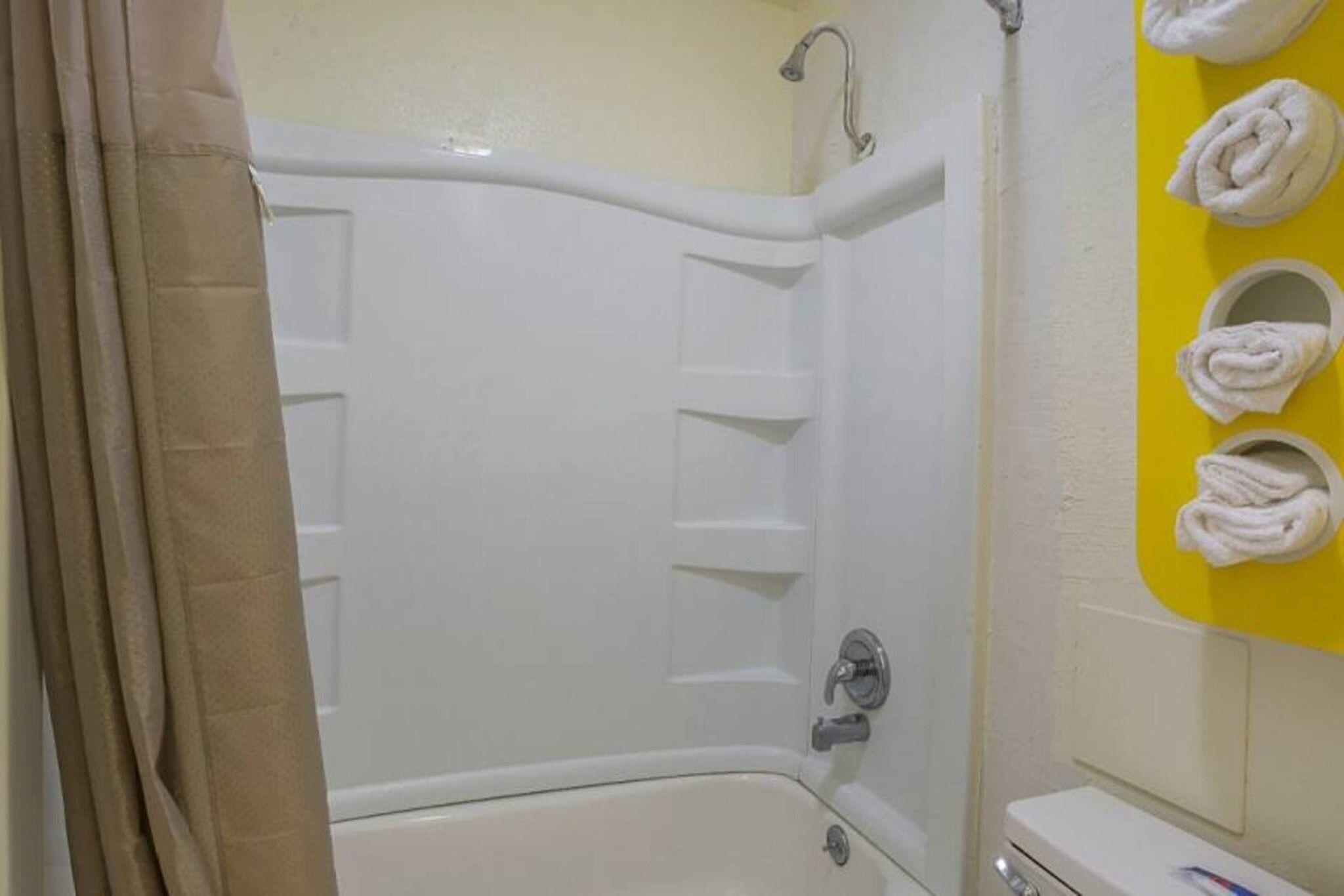 A bathroom with a bathtub, a shower, and a towel rack with towels.