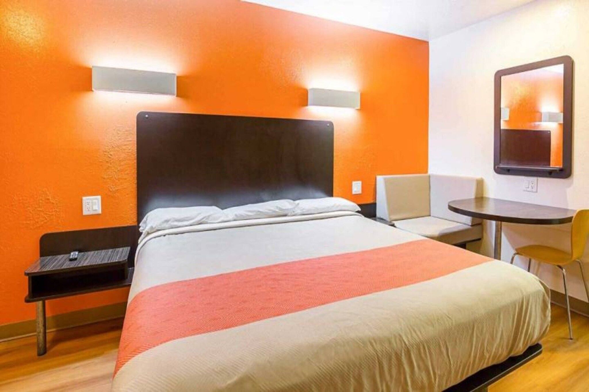 A hotel room with a bed, a desk, a chair, and a small table.