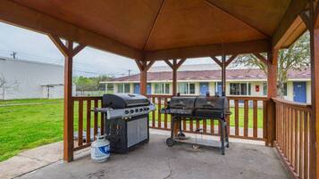 A covered outdoor area with two barbecue grills and a propane tank.