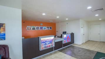 A hotel reception area with a counter, a wall-mounted sign, and a door.