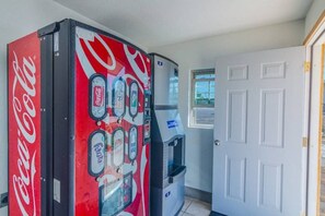 Máquina de Coca-Cola e bebedouro em um quarto com porta branca e janela.