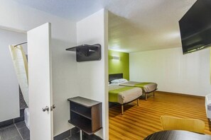 A hotel room with a bed, a desk, a TV, and a green wall.