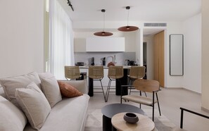 A modern living room with a sofa, chairs, a coffee table, and a kitchen in the background. - Seaside suite at 42 Eilat (Eilat)