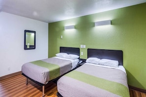 Ein Zimmer mit zwei Einzelbetten, einem Spiegel und einer grünen Wand.