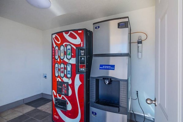 Ein Getränkeautomat mit Coca-Cola-Logo und einem Wassenspender mit einem Schild.