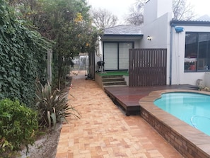 A backyard with a swimming pool, a brick pathway, and a wooden deck. - Stellenbosch On the Go! (Stellenbosch)