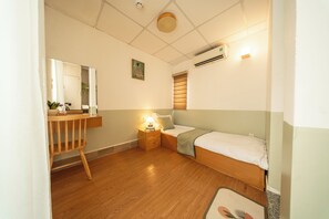 Ein gemütliches Zimmer mit einem Bett, einem Nachttisch mit Lampe, einem Sessel und einem kleinen Schreibtisch mit Spiegel.