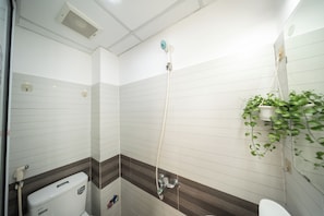 Ein Badezimmer mit Dusche, Toilette und einer Zimmerpflanze.