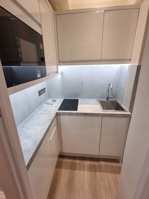 A compact kitchen with a built-in microwave, a sink, and a countertop. - Light-filled Studio in Prestigious Chelsea (London)