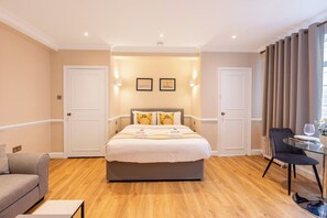 Une chambre d’hôtel avec un lit, un canapé, une table en verre et une chaise.