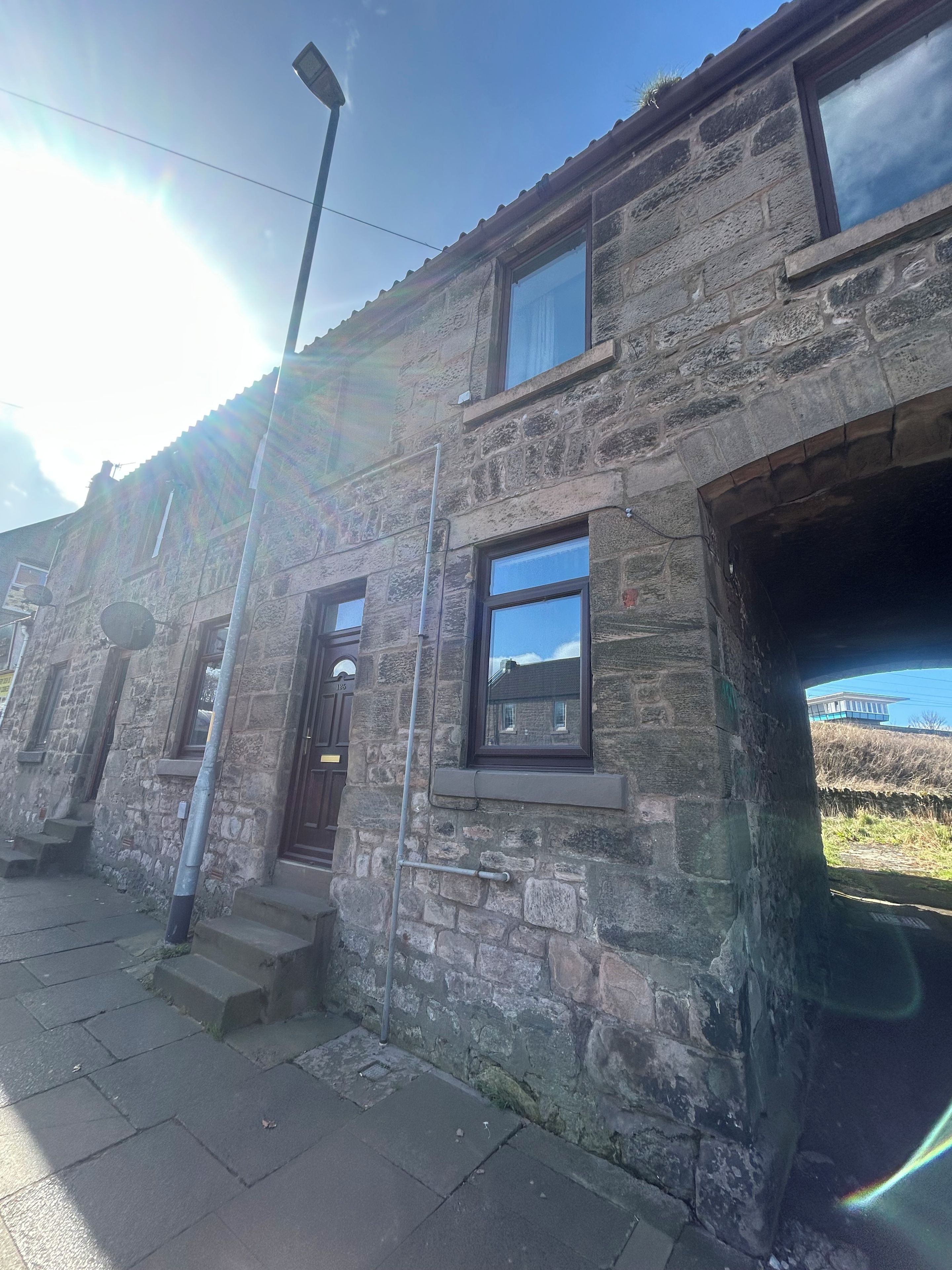 Un edificio de piedra con una sola entrada visible, una ventana pequeña y una escalera que conduce a la entrada.