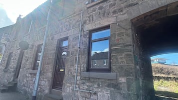 Un edificio de piedra con una sola entrada visible, una ventana pequeña y una escalera que conduce a la entrada.