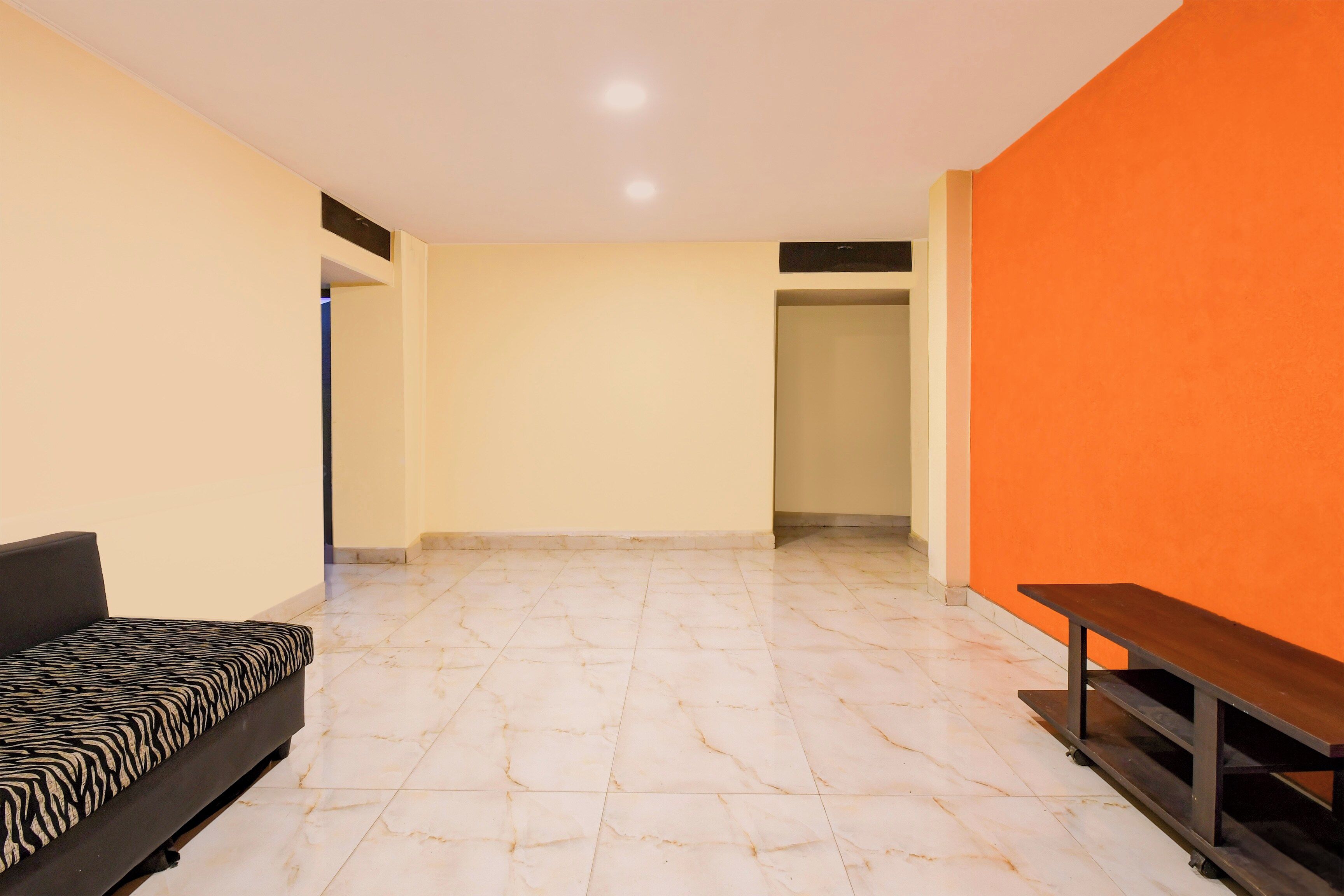 A room with a sofa, a bench, and a tiled floor.