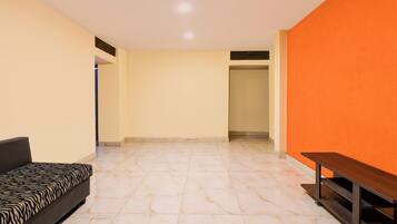 A room with a sofa, a bench, and a tiled floor.