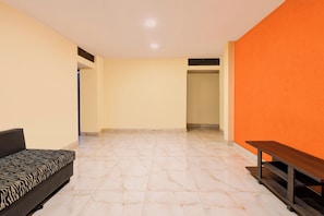 Una habitación con un sofá, un banco y suelo de baldosas.