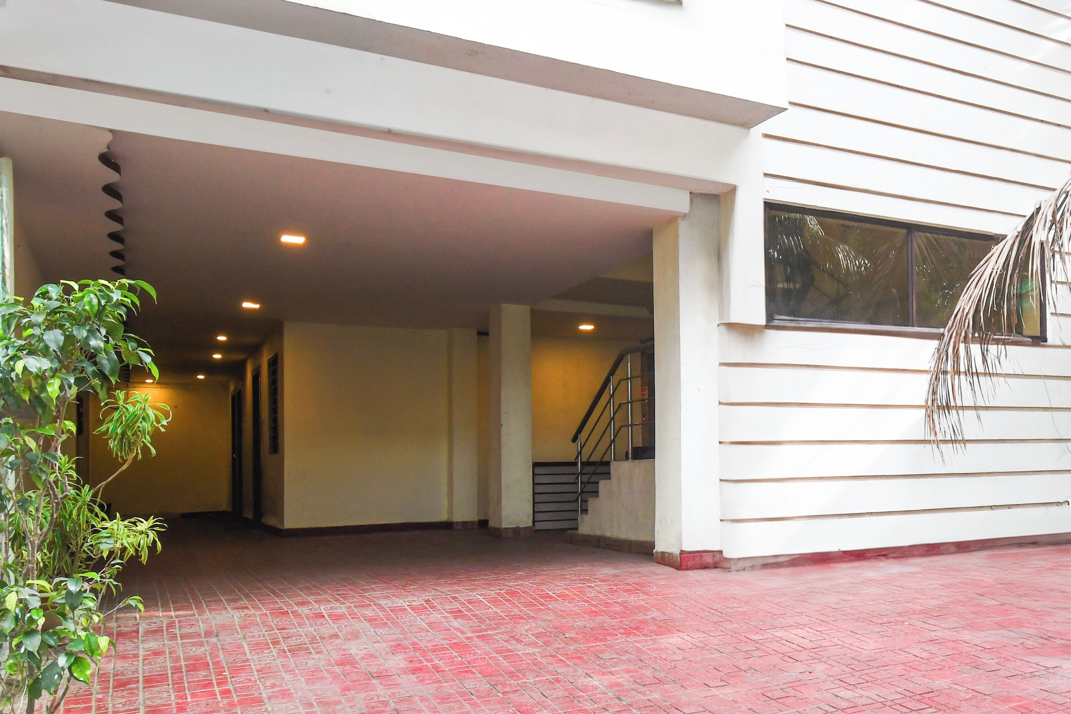 Una entrada de edificio con piso de ladrillo rojo, una escalera y una planta.