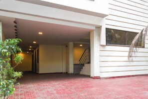 A building entrance with a red brick floor, a staircase, and a plant.