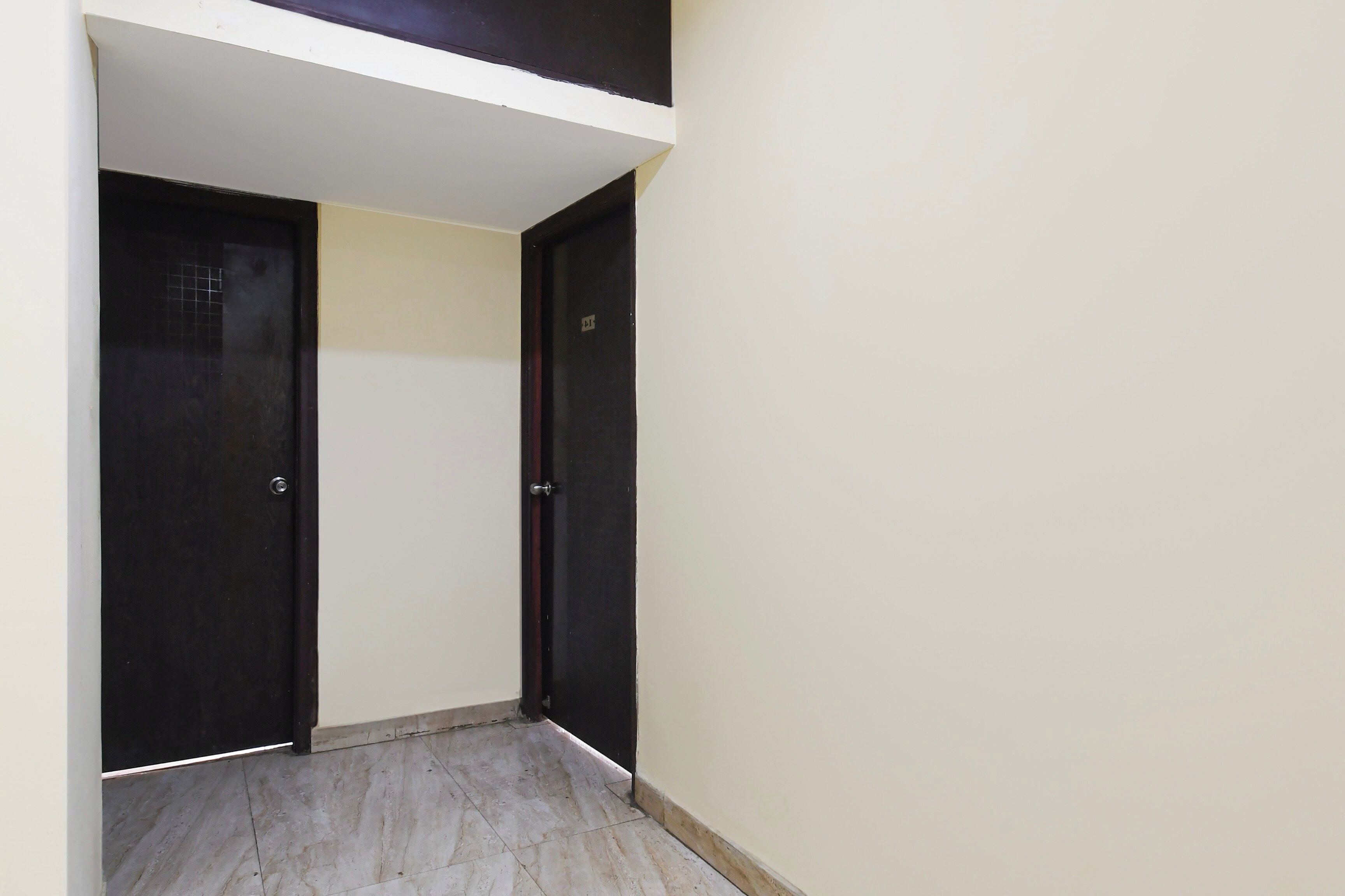 Un pasillo estrecho con dos puertas negras, una a cada lado, que dan a una habitación.