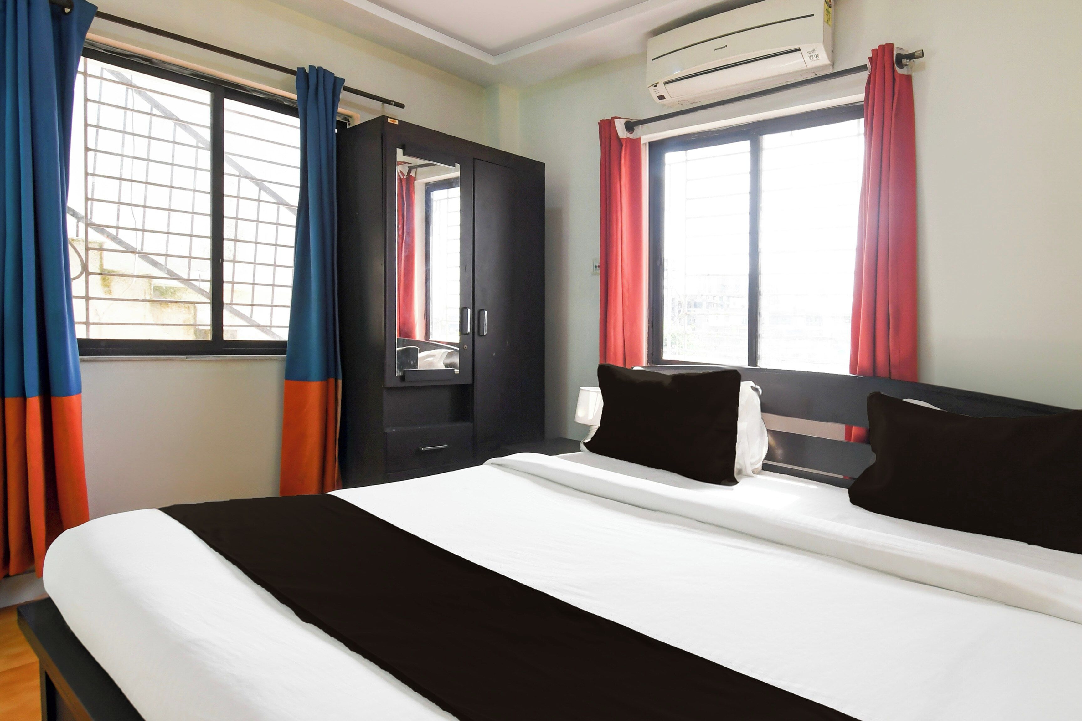 A hotel room with a bed, a wardrobe, and an air conditioning unit.