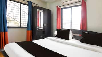 A hotel room with a bed, a wardrobe, and an air conditioning unit.
