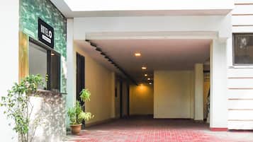 A hotel corridor with a stone wall, potted plants, and a sign indicating the hotel name.