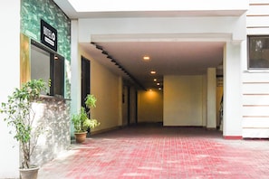 Pasillo de hotel con pared de piedra, plantas en macetas y un cartel con el nombre del hotel.
