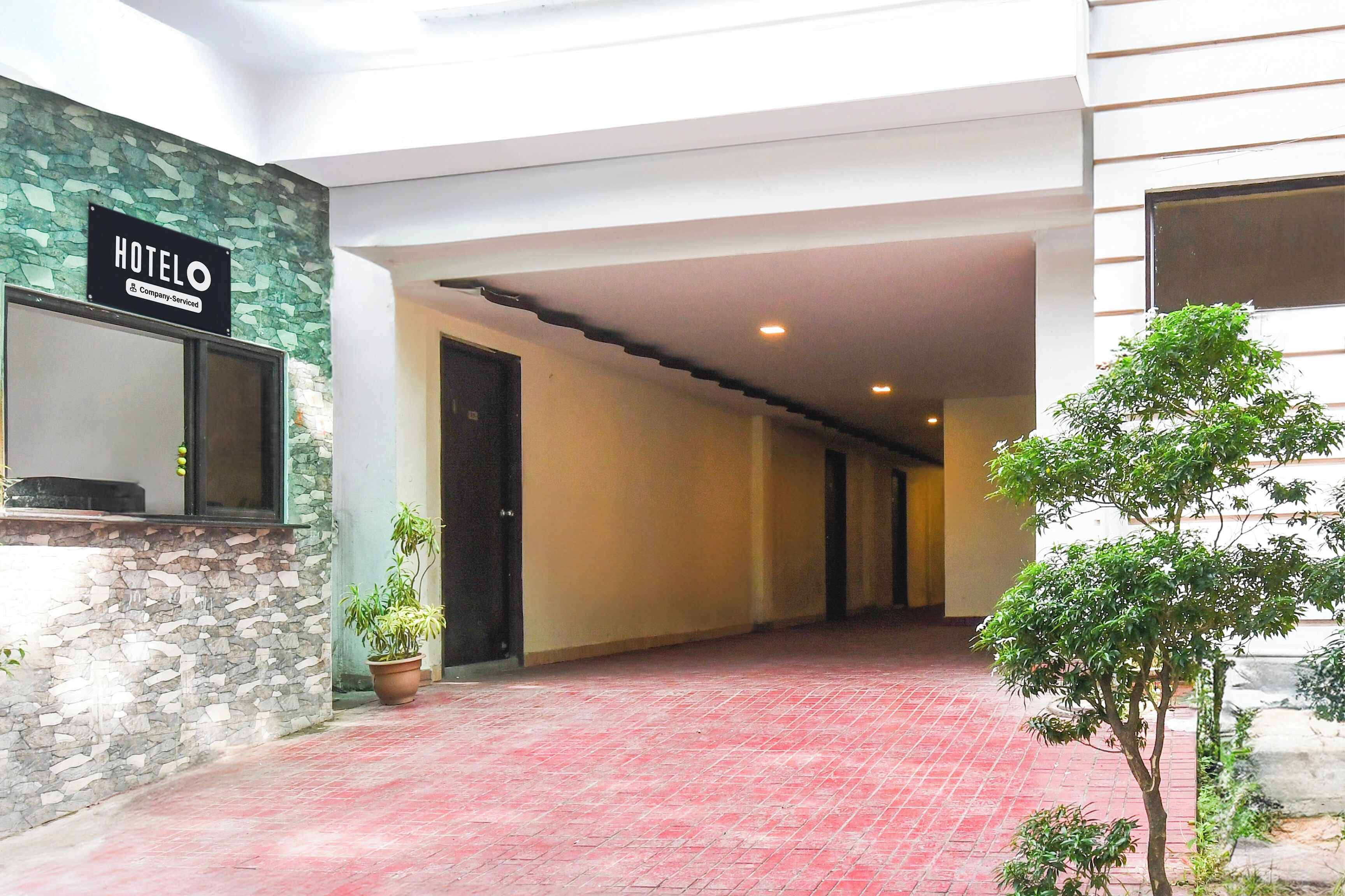 A hotel corridor with a stone wall, a sign indicating it's a company-serviced hotel, and a red-tiled floor.