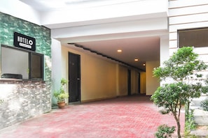 A hotel corridor with a stone wall, a sign indicating it's a company-serviced hotel, and a red-tiled floor.