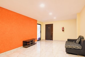 A room with a sofa, a bench, a door, and a fire extinguisher.