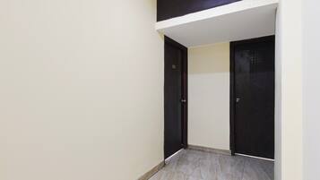 A narrow hallway with two dark doors, a light-colored wall, and a tiled floor.