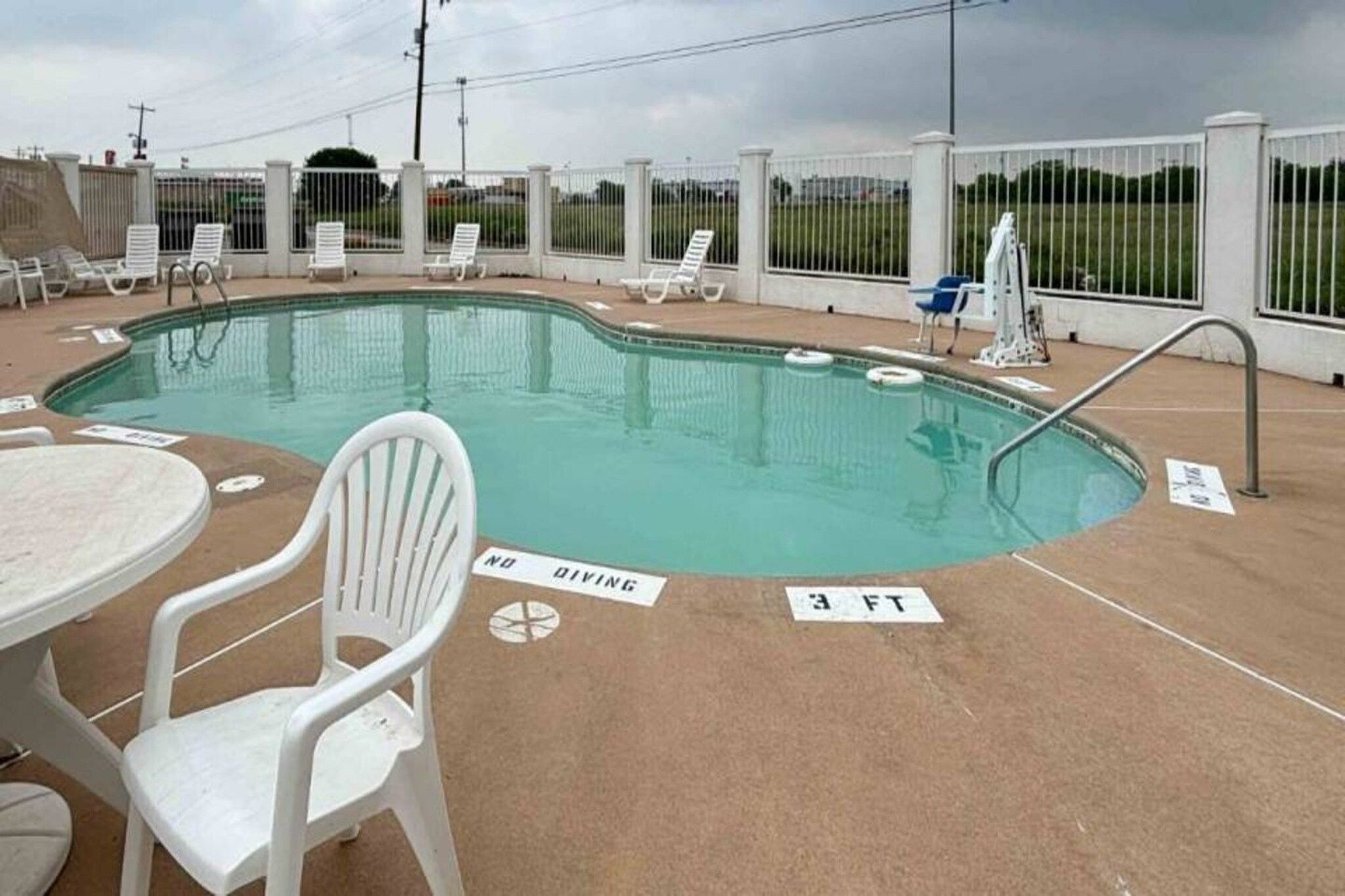 A swimming pool with lounge chairs and a diving sign.