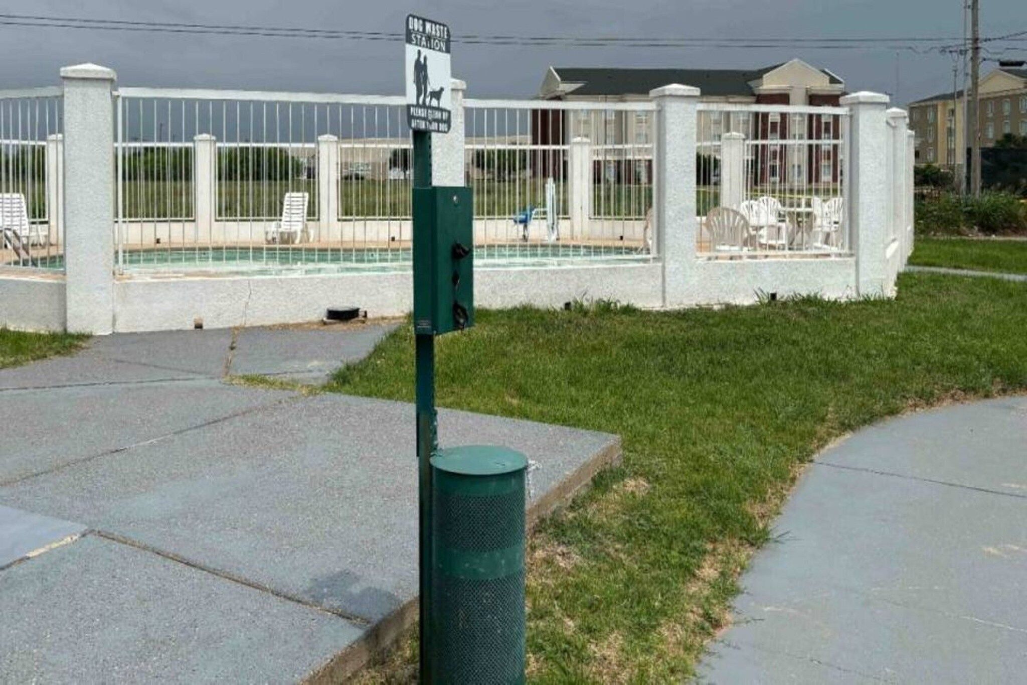 A fenced area with a trash bin and a sign indicating a dog waste station.