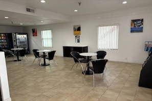 A spacious room with a tiled floor, a vending machine, a counter, and several chairs arranged around a table. - 2 Queen Beds | Non-Smoking, Kitchen (Abilene)
