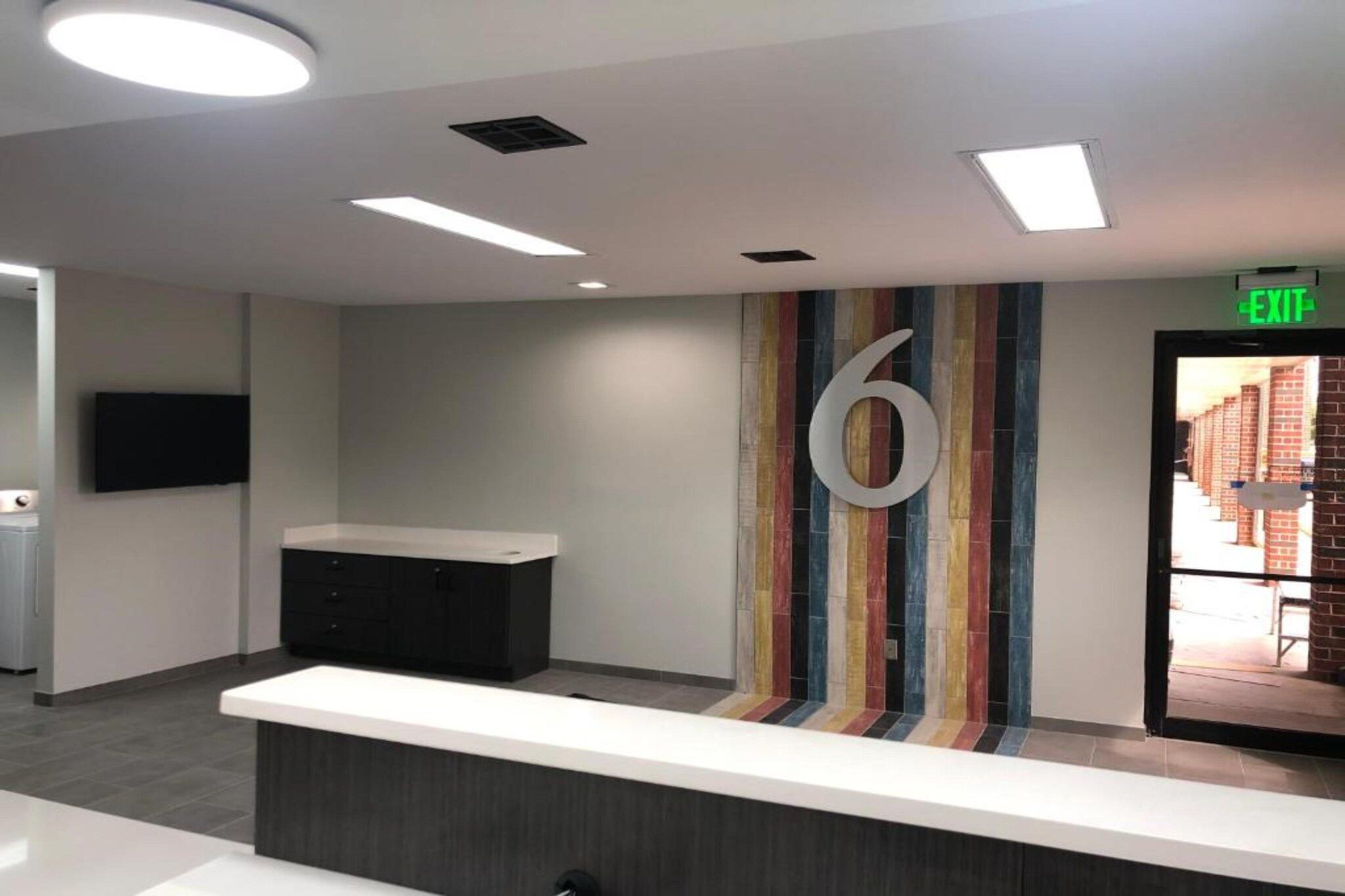 A reception area with a counter, a large number '6' on the wall, and an exit sign.