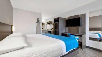 A hotel room with a large bed, a desk, a flat-screen TV, and a built-in wardrobe.