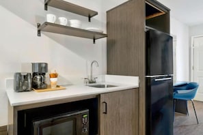 Une cuisine compacte équipée d’un réfrigérateur encastré, d’une machine à café, d’un évier et d’un four à micro-ondes.