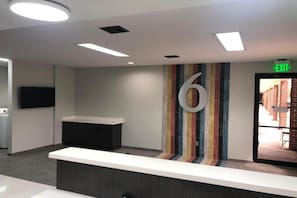 Un espace d’accueil avec un comptoir, un grand chiffre « 6 » peint sur le mur et un panneau indiquant la sortie.