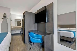 Une chambre d’hôtel équipée d’un lit, d’un bureau, d’une chaise, d’une télévision et d’un miroir.