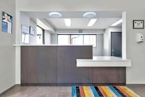 A reception area with a wooden reception desk, a white counter, and a colorful striped rug on the floor. - 2 Queen Beds | Smoking, Kitchen (Austin TX)