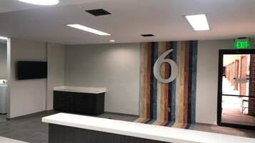 A reception area with a counter, a large number '6' on the wall, and an exit sign.