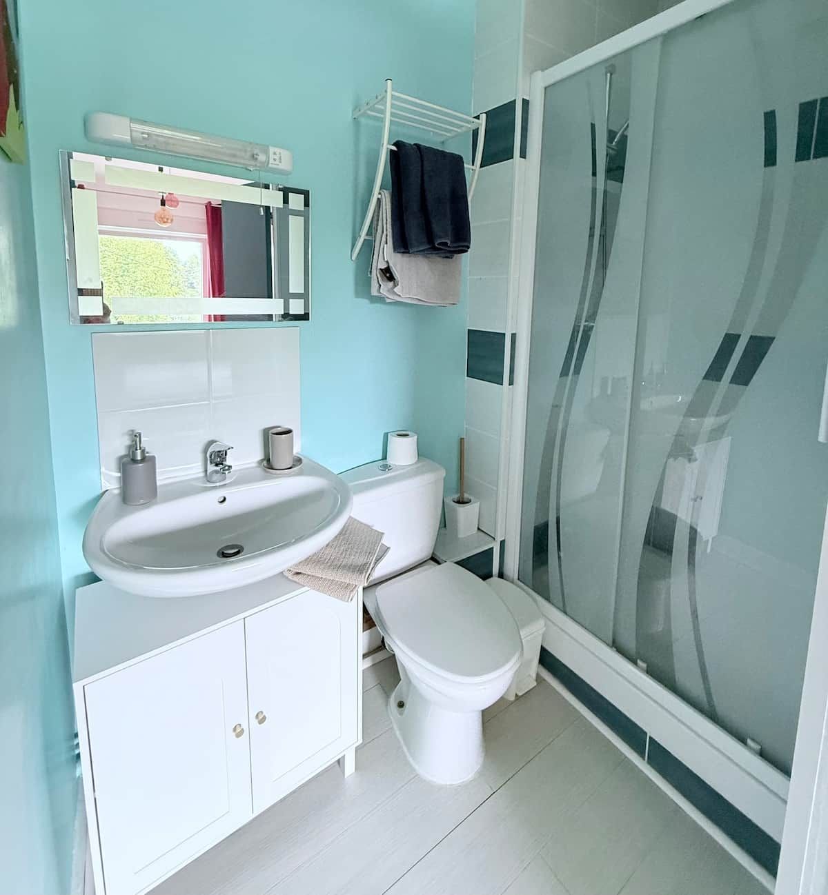 A bathroom with a white sink, toilet, and glass shower enclosure.