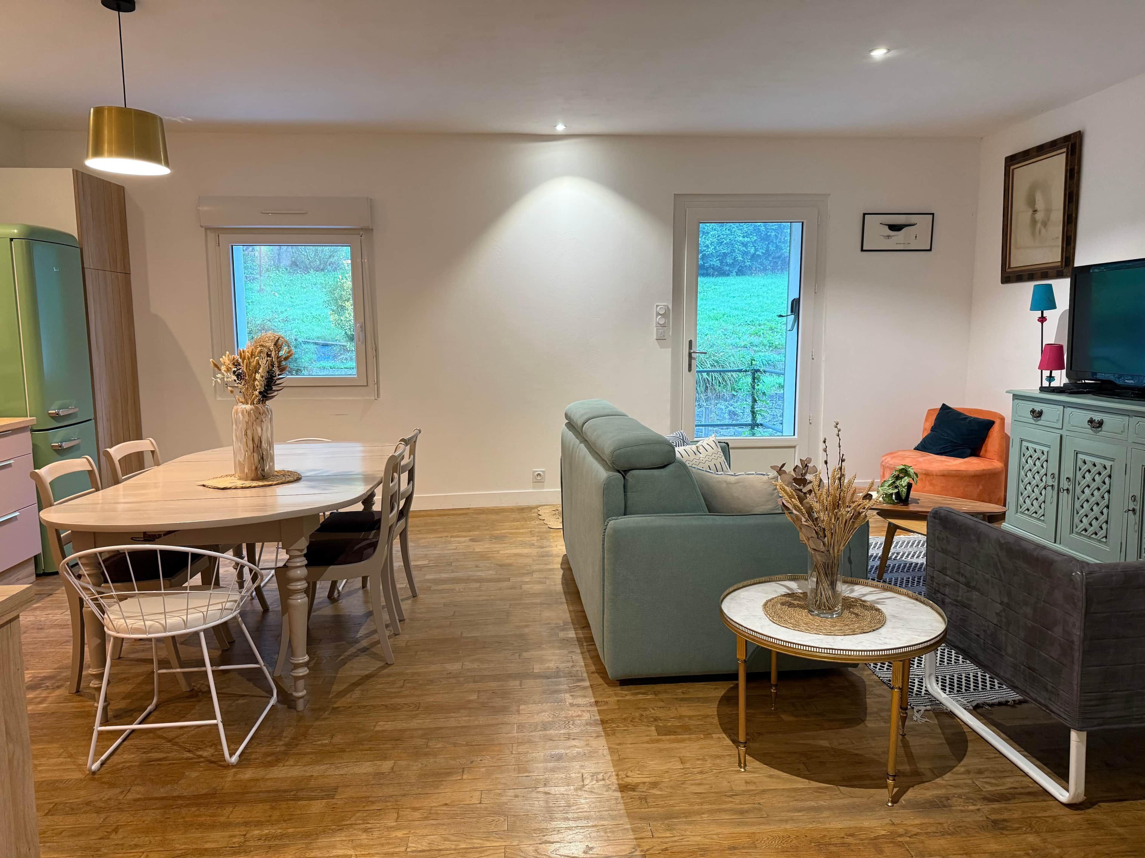 A modern living room with a dining area, a sofa, a television, and a cabinet.