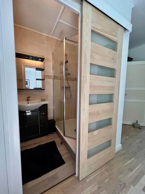 Uma casa de banho moderna com cabine de duche de vidro, lavatório e espelho.