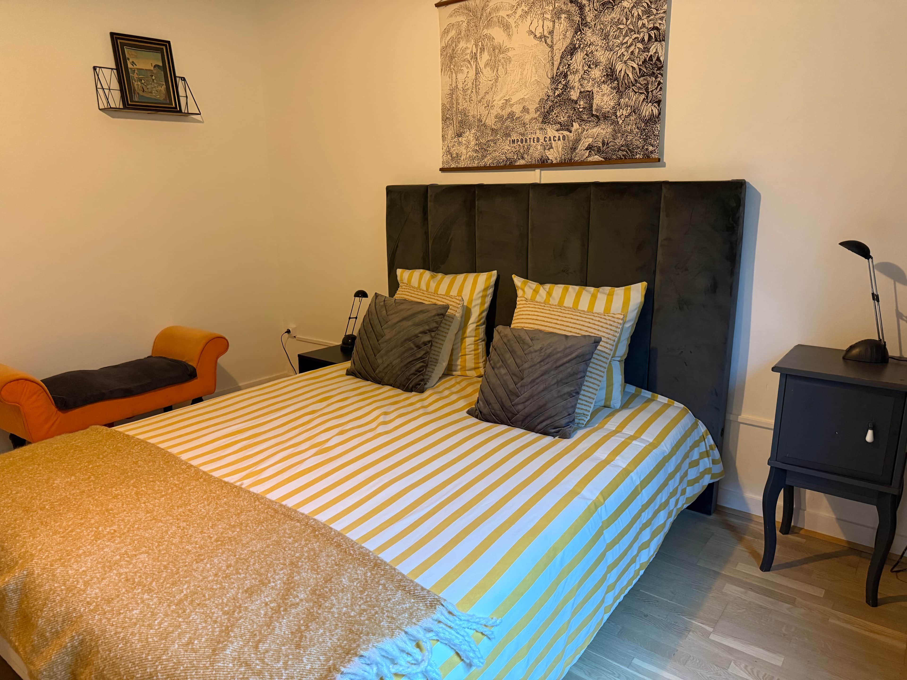 Een slaapkamer met een bed, nachtkastjes, een stoel en een wanddecoratie.