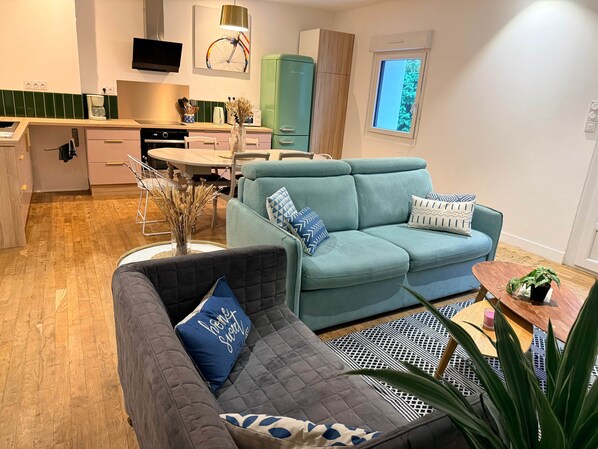 A modern living room with a grey sofa, a teal sofa, and a coffee table with a plant.