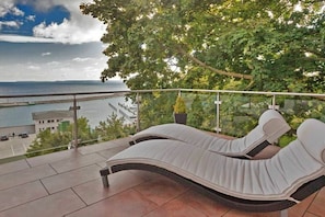 A balcony with two lounge chairs, a view of the sea, and a building in the background. - Holiday apartment with 2 bedrooms (Sassnitz auf Rügen)