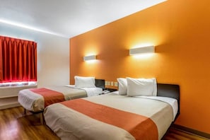 A hotel room with two beds, a red curtain, and a wall-mounted light fixture.
