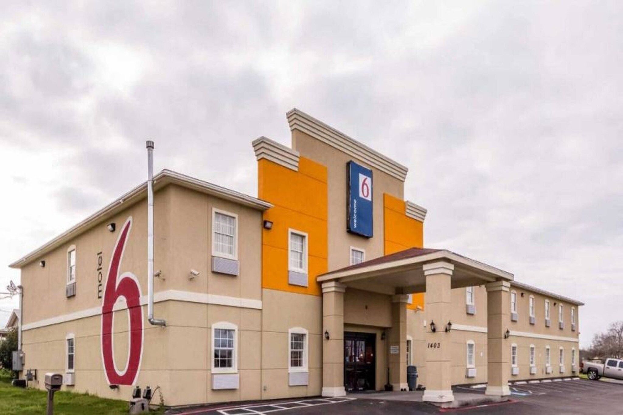 Een hotel met een opvallend nummer '6' op de gevel, een 'Welcome'-bord en het nummer '1403' op het gebouw.