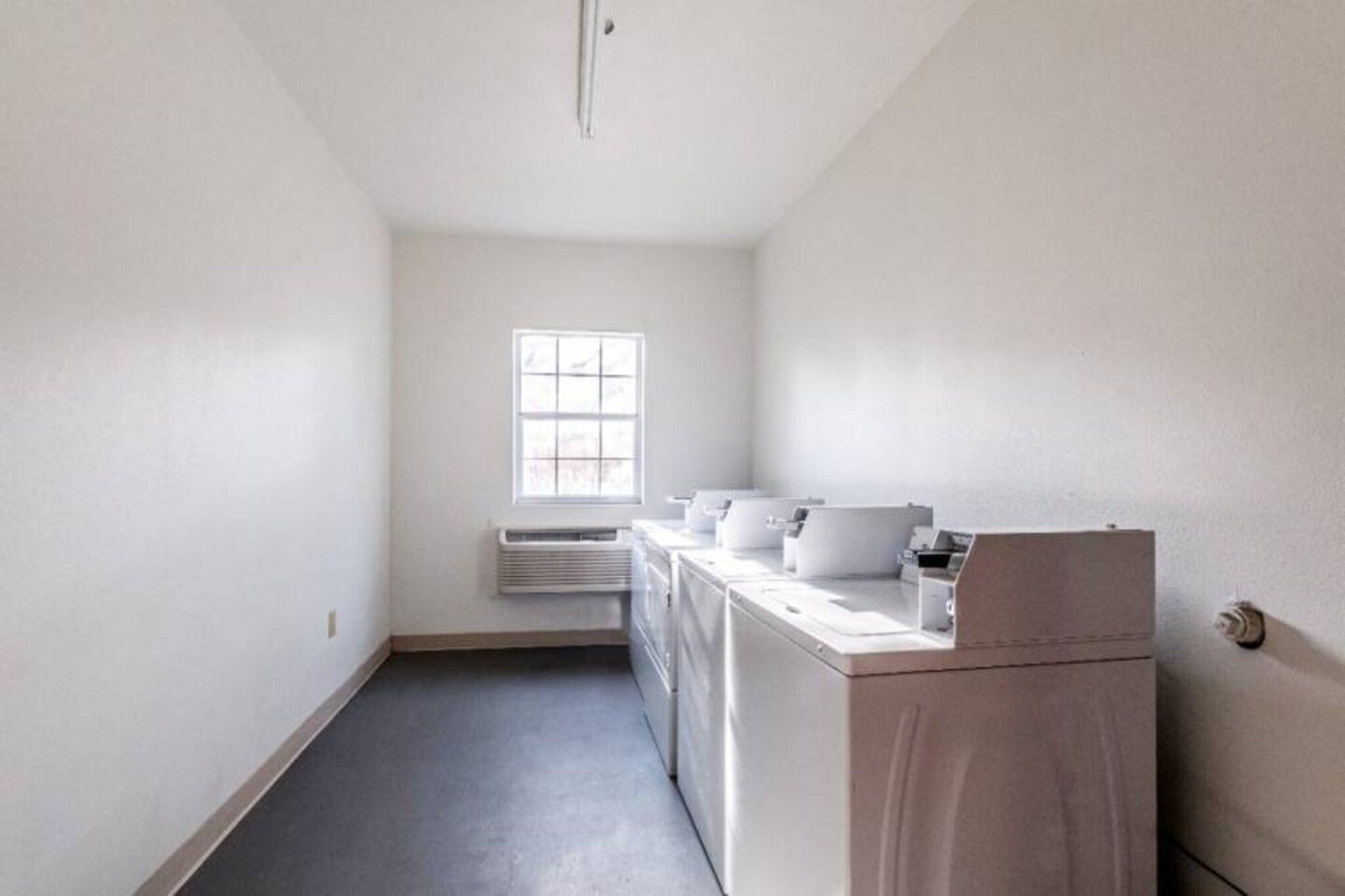 A laundry room with a window, a washing machine, and a dryer.
